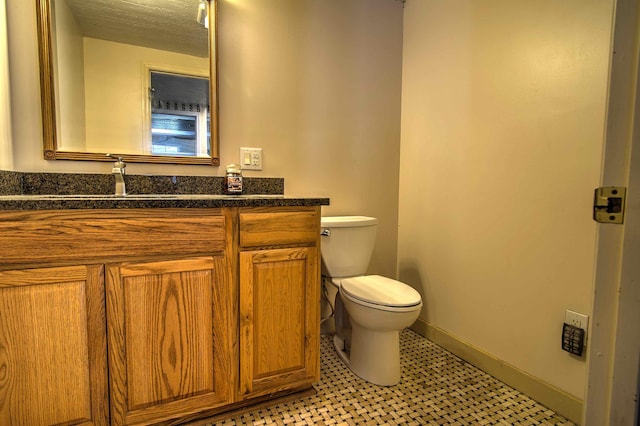 half bath with toilet, tile patterned floors, and vanity