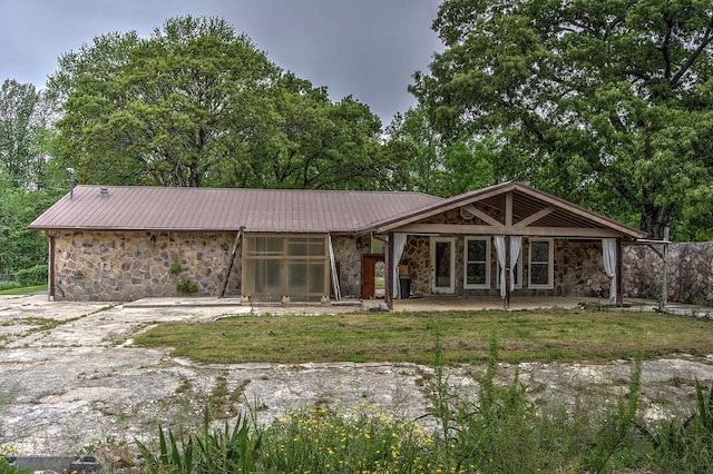 back of property featuring metal roof, a patio area, and stone siding