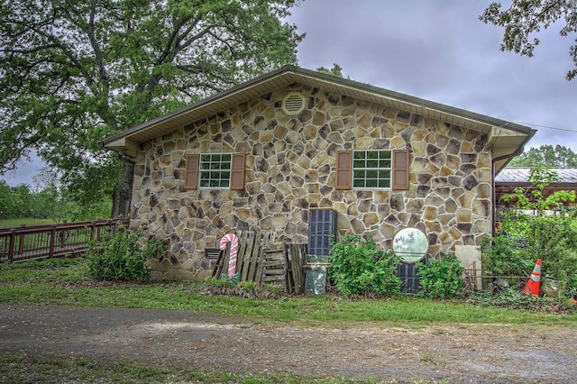 view of home's exterior featuring fence and stone siding