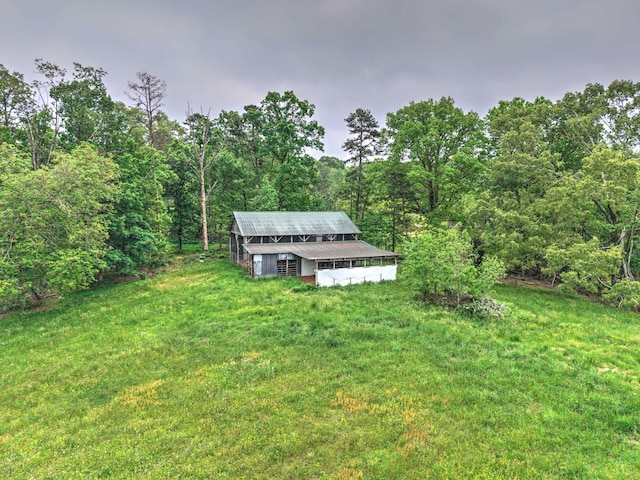 view of yard featuring a wooded view and an outbuilding