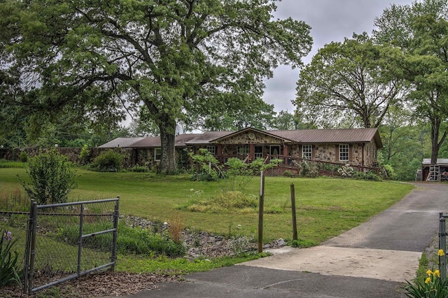 ranch-style home featuring fence, metal roof, a front lawn, and stone siding