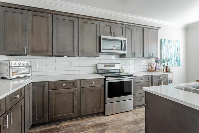 1826 Seven Pines Ln, Chattanooga, TN 37415 - kitchen with appliances with stainless steel finishes, ornamental molding, backsplash, wood finished floors, and dark brown cabinets