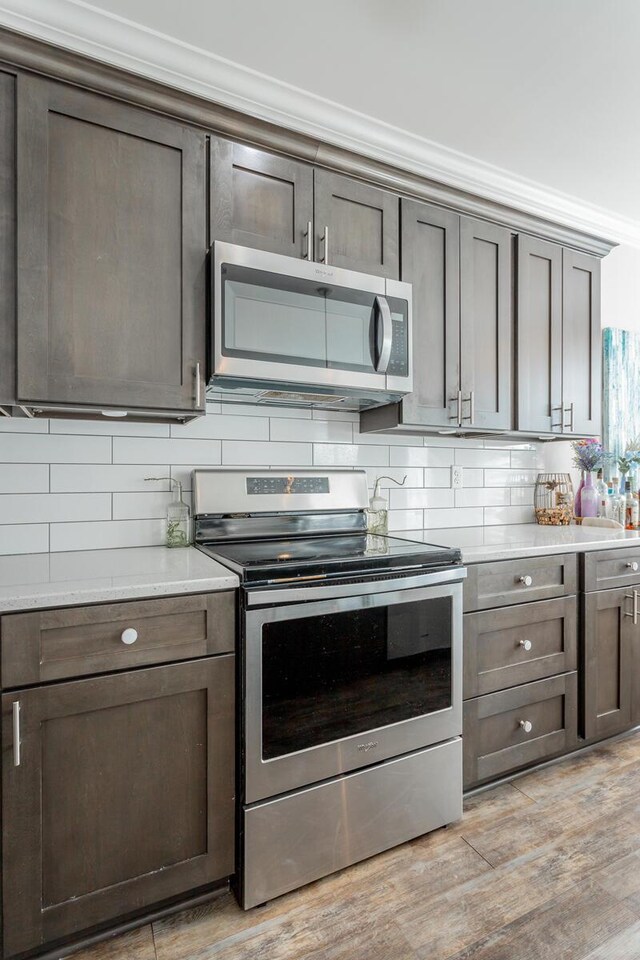 1826 Seven Pines Ln, Chattanooga, TN 37415 - kitchen with stainless steel appliances, decorative backsplash, light countertops, light wood finished floors, and crown molding