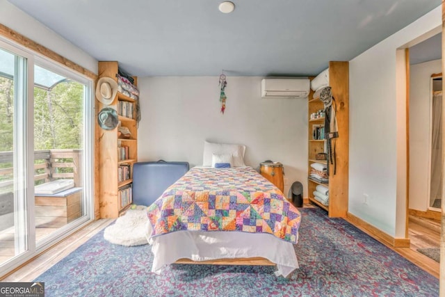 bedroom with an AC wall unit and wood finished floors