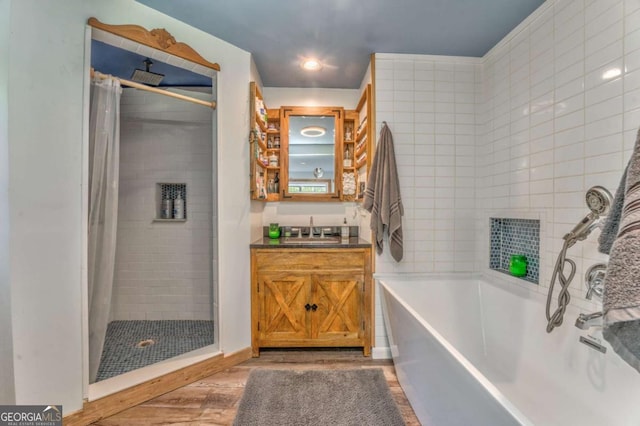 full bathroom with vanity, wood finished floors, a garden tub, and a stall shower