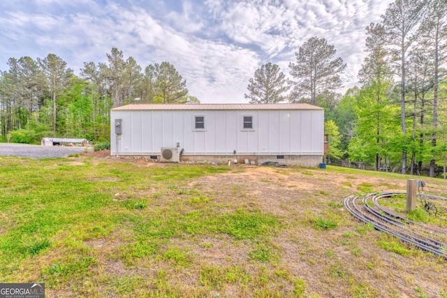 rear view of property with board and batten siding, ac unit, crawl space, and metal roof