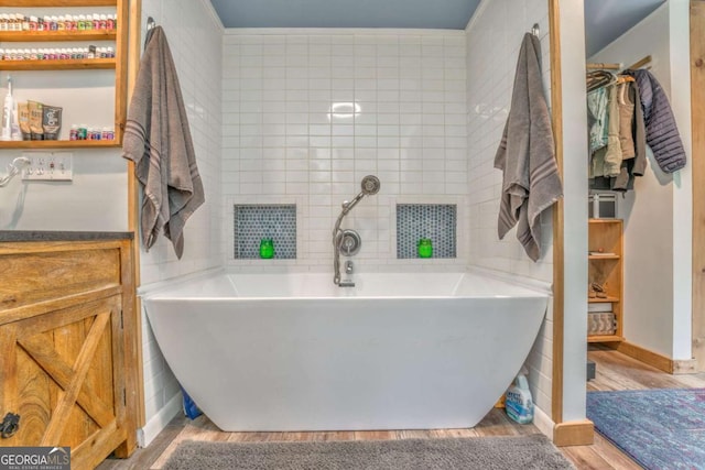 full bathroom with a soaking tub, wood finished floors, and vanity