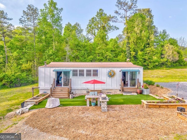 back of property with entry steps, board and batten siding, and a yard