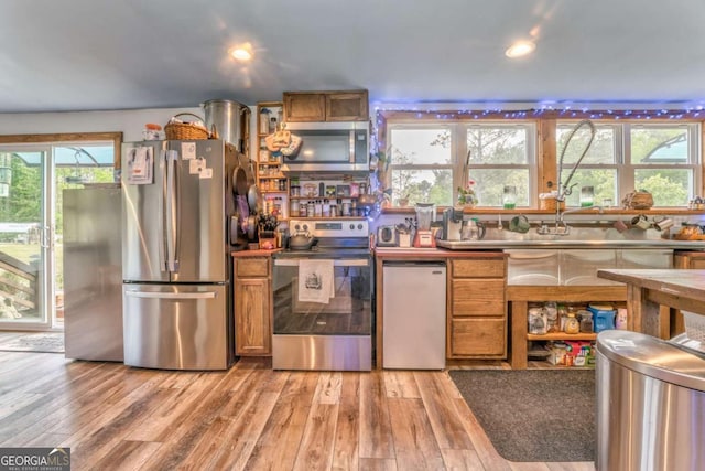 kitchen featuring recessed lighting, light wood finished floors, appliances with stainless steel finishes, and brown cabinets