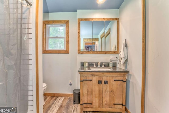 full bathroom with vanity, a shower, wood finished floors, toilet, and baseboards