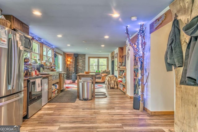 kitchen featuring recessed lighting, a wood stove, light wood finished floors, and stainless steel appliances