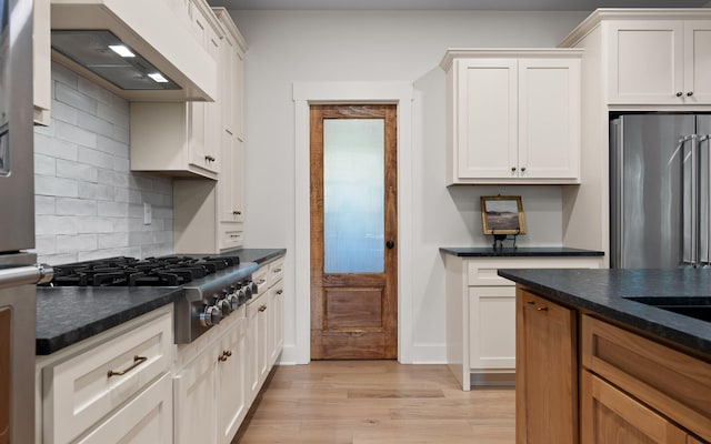 6949 Sawyer Rd, Signal Mountain, TN 37377 - kitchen with custom exhaust hood, stainless steel appliances, light wood-type flooring, decorative backsplash, and white cabinetry