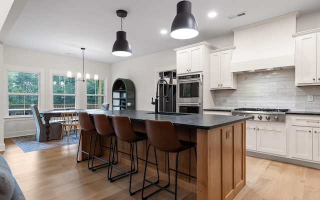 6949 Sawyer Rd, Signal Mountain, TN 37377 - kitchen with stainless steel appliances, dark countertops, light wood-style floors, decorative backsplash, and a chandelier