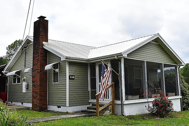 view of home's exterior with a chimney, crawl space, a sunroom, metal roof, and entry steps