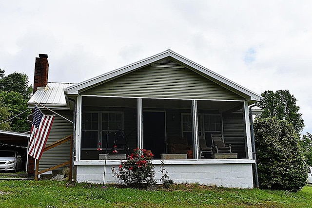 back of house with a chimney, a sunroom, and a yard