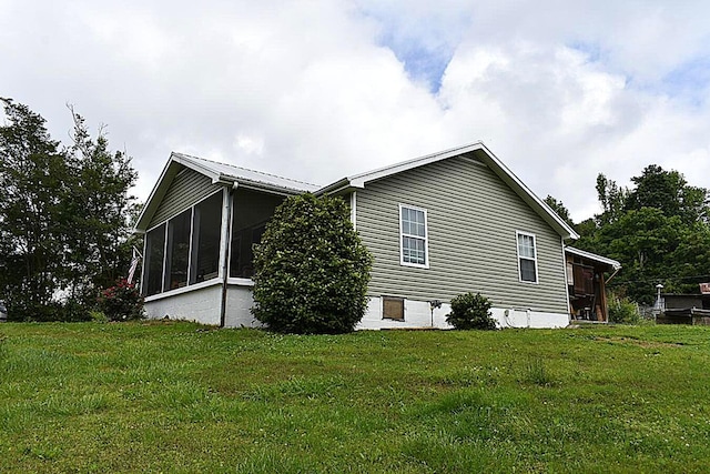 view of home's exterior with a sunroom and a yard