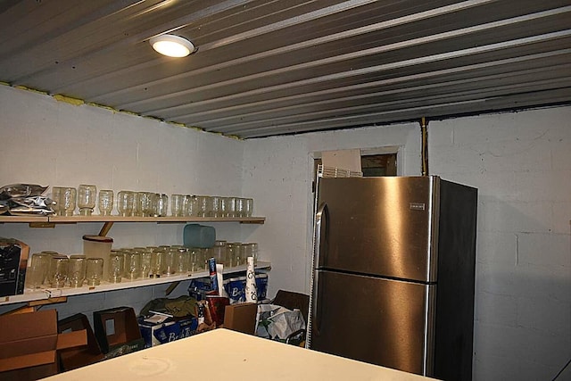 kitchen with freestanding refrigerator, concrete block wall, and open shelves