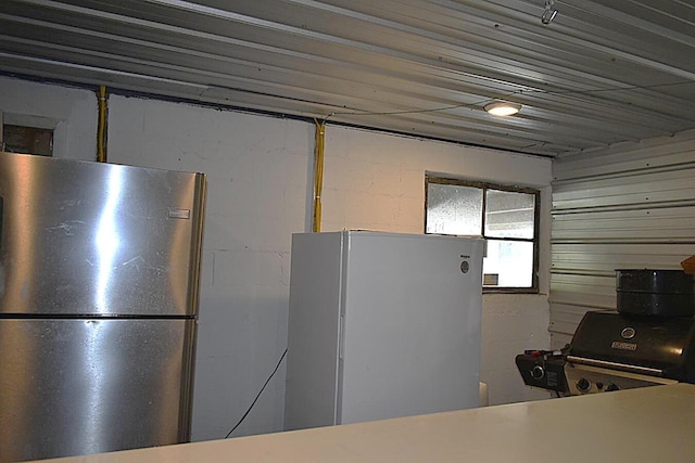 kitchen with freestanding refrigerator and concrete block wall