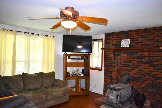 living room featuring wood finished floors, ceiling fan, and a wood stove