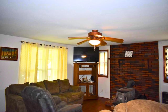 living room featuring a wood stove, ceiling fan, and wood finished floors