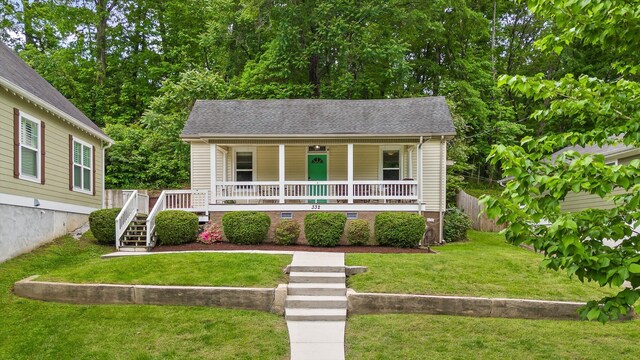 bungalow-style home with a porch, a front yard, roof with shingles, fence, and stairs