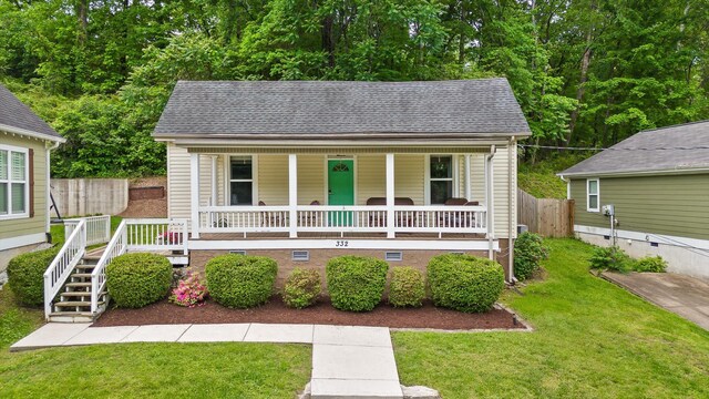 bungalow-style house with a porch, a front yard, stairway, fence, and a shingled roof