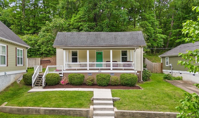 bungalow featuring covered porch, stairway, fence, a front lawn, and a shingled roof