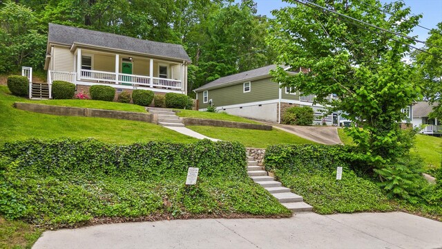 view of front of house featuring stairs, a porch, and a front lawn
