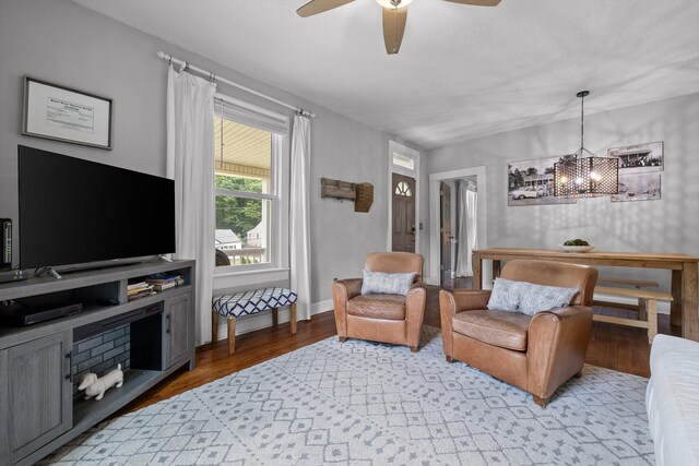 living room featuring ceiling fan with notable chandelier and light wood-type flooring