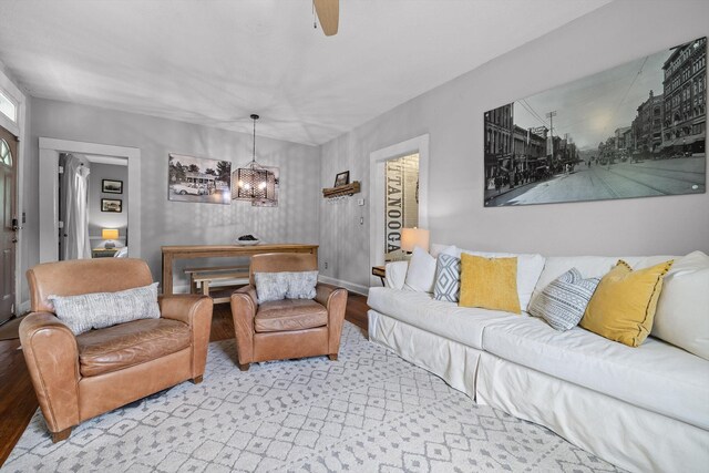 living area with baseboards, ceiling fan with notable chandelier, and wood finished floors