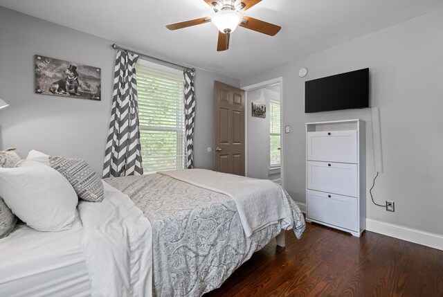 bedroom featuring baseboards, multiple windows, dark wood-style flooring, and ceiling fan