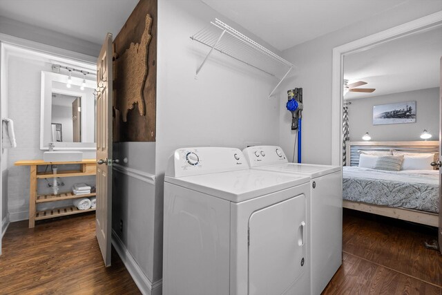 laundry area with laundry area, washing machine and dryer, a sink, baseboards, and dark wood-type flooring