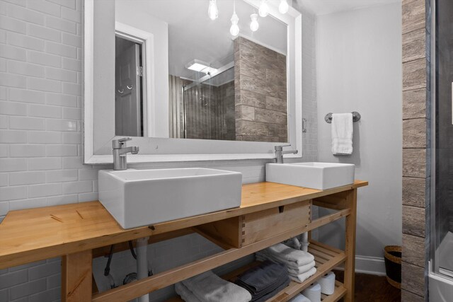 full bathroom featuring double vanity, a sink, and a stall shower