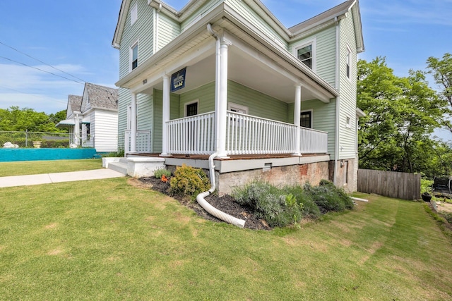 view of side of property featuring a porch, a yard, and fence