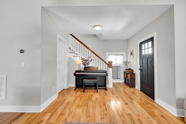 entrance foyer with stairs, baseboards, visible vents, and hardwood / wood-style flooring