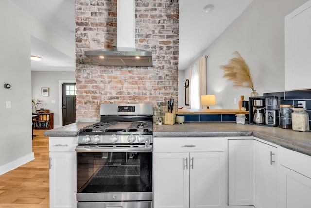 kitchen featuring exhaust hood, white cabinets, stainless steel gas range oven, and light wood-type flooring