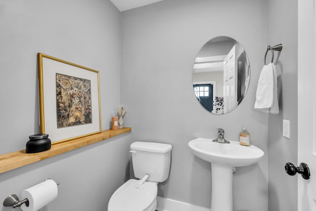 half bath with baseboards and toilet