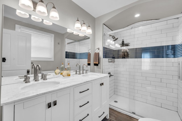 full bath with double vanity, tiled shower, and a sink