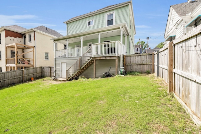 rear view of house featuring a lawn, stairs, and a fenced backyard