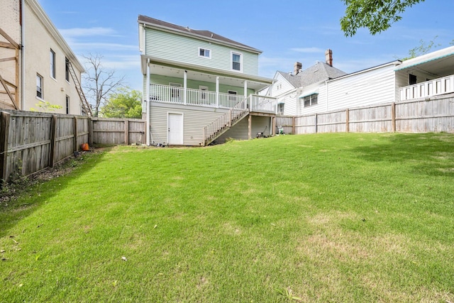 rear view of property featuring a fenced backyard, stairs, and a lawn
