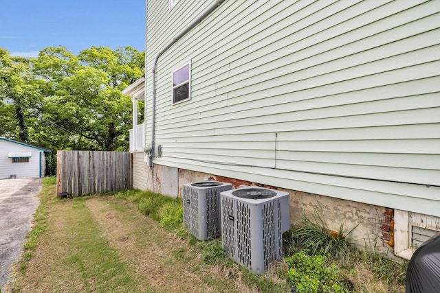 view of home's exterior with fence, driveway, and cooling unit