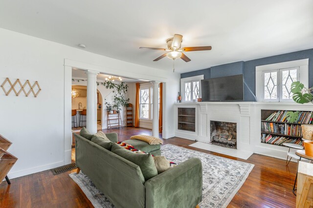 225 Hemphill Ave, Chattanooga, TN 37411 - living room featuring a brick fireplace, a ceiling fan, baseboards, ornate columns, and dark wood-style floors