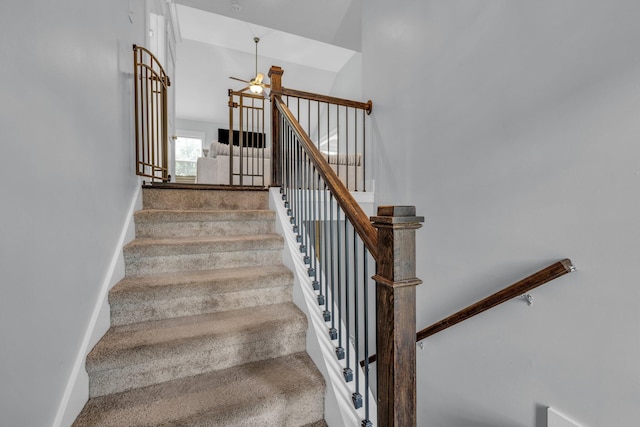 stairs featuring baseboards, a ceiling fan, a towering ceiling, and carpet flooring