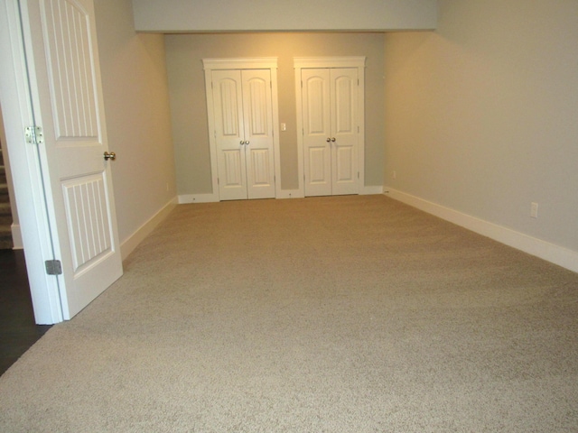 unfurnished bedroom with two closets, carpet flooring, and baseboards