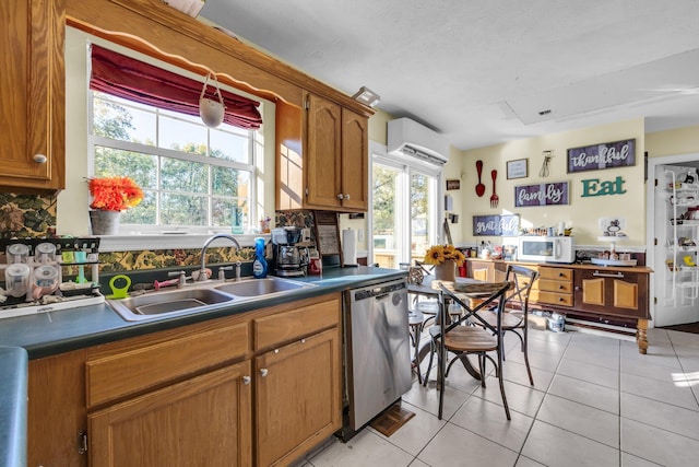 kitchen with stainless steel dishwasher, dark countertops, white microwave, a sink, and light tile patterned floors
