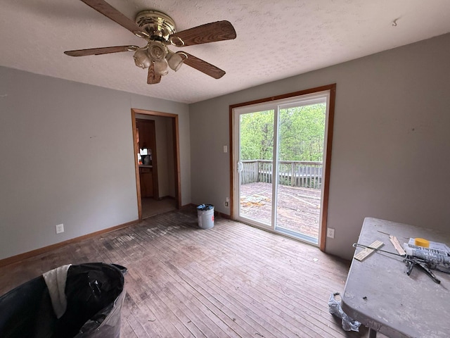 interior space with a ceiling fan, hardwood / wood-style floors, a textured ceiling, and baseboards