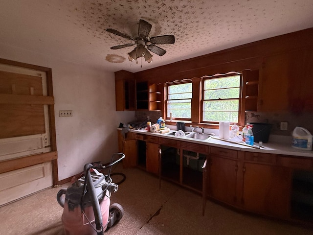 kitchen with brown cabinets, a sink, open shelves, ceiling fan, and light countertops