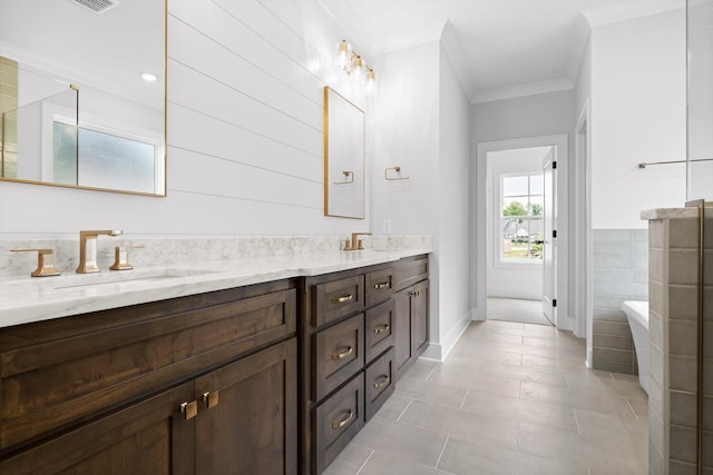 full bathroom featuring double vanity, a sink, crown molding, tile patterned flooring, and a freestanding tub