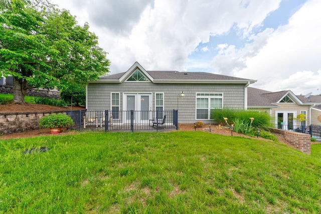 rear view of house with a lawn and fence