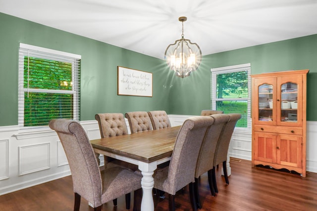dining room featuring a decorative wall, dark wood-style flooring, wainscoting, and a notable chandelier